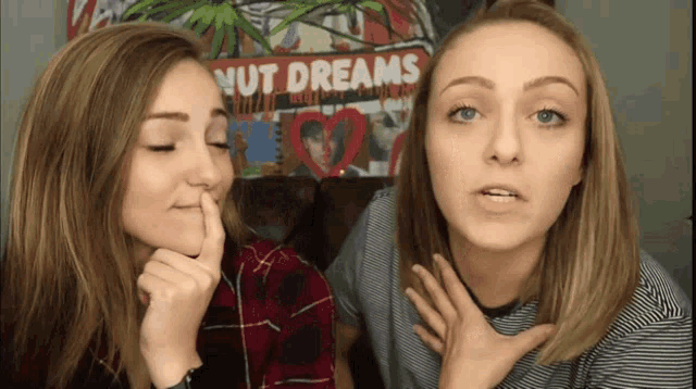 two girls are talking in front of a nut dreams poster