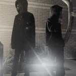 a man in a hooded jacket is standing next to another man in a hooded jacket .