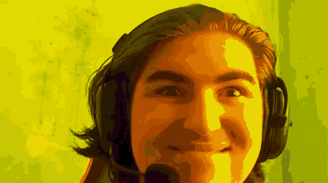 a young man wearing headphones and a microphone makes a face