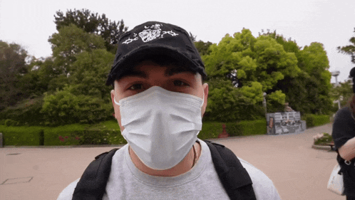 a man wearing a white face mask and a black hat with a tiger on it