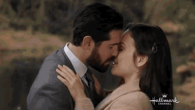 a man and a woman are kissing in front of a hallmark channel logo