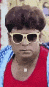 a man wearing sunglasses and a red shirt is looking at the camera