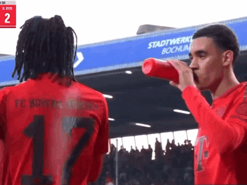 a man wearing a red shirt with the number 17 on it drinks from a red bottle