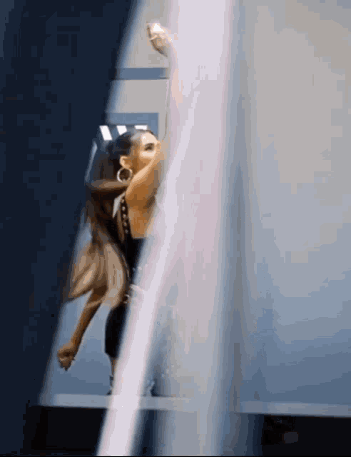 a woman in a black dress is standing on a staircase