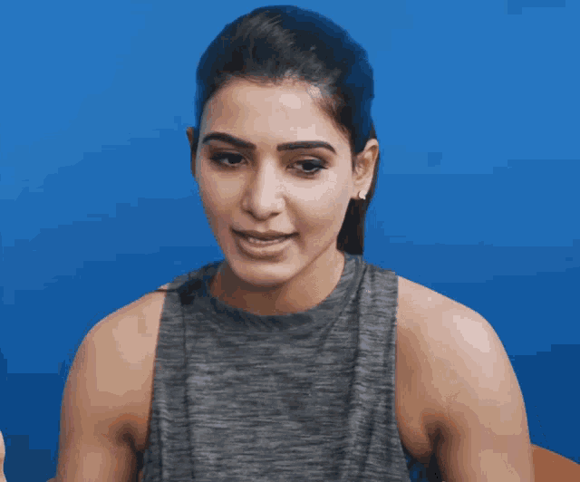 a woman wearing a grey tank top is making a funny face