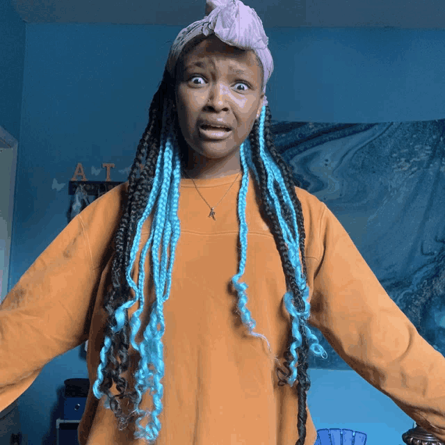 a girl with blue braids is standing in front of a blue wall with the letter a on it