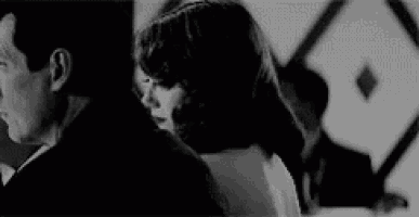 a man and a woman are standing next to each other and looking at each other in a black and white photo .