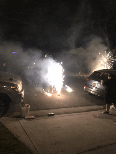 a fireworks display in a driveway with a car with a license plate that starts with the letter a
