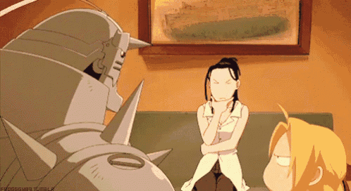 a woman is sitting on a couch with her arms crossed while a robot stands behind her .