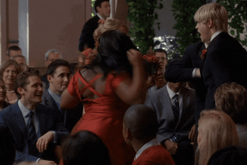a woman in a red dress is dancing in front of a crowd