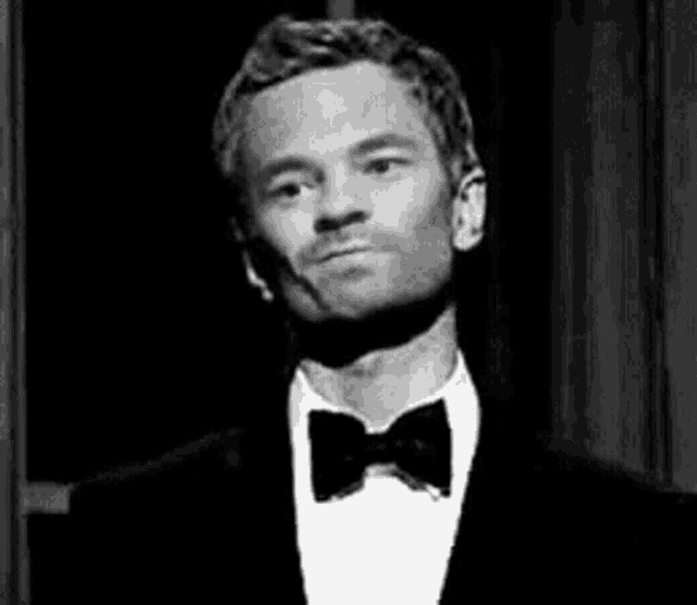 a black and white photo of a man in a tuxedo and bow tie .
