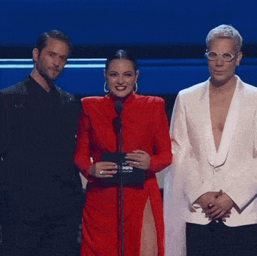 a woman in a red dress stands in front of a microphone at a billboard awards ceremony