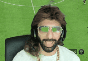 a man wearing a wig and sunglasses is sitting in front of a soccer field ..