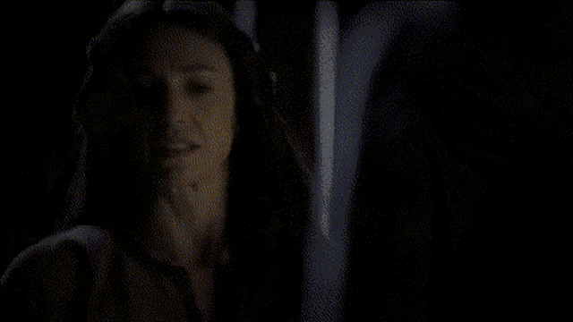 two women are shaking hands in front of a fireplace in a room .