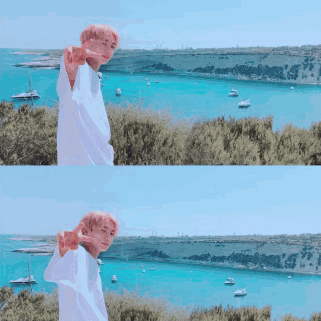 a man in a white shirt is standing on a hill overlooking a body of water