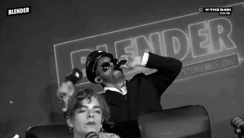 a black and white photo of a man and woman in front of a blender sign