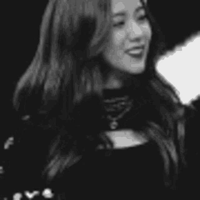 a black and white photo of a woman with long hair wearing a black shirt .