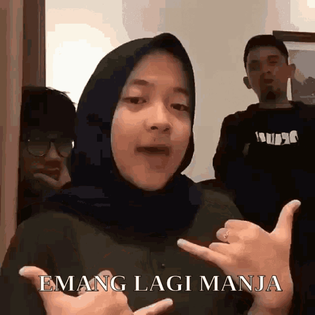 a woman wearing a hijab is making a hand gesture while standing next to a man .