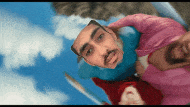 a man in a blue shirt and a woman in a pink shirt are looking up at the camera