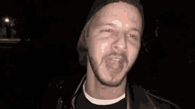 a man with a beard wearing a hat and a leather jacket