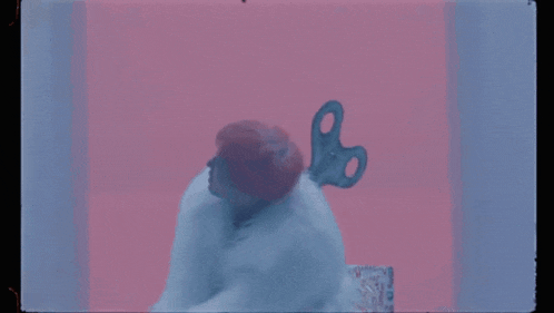 a person with a wind up key in their hair is sitting on a bed .