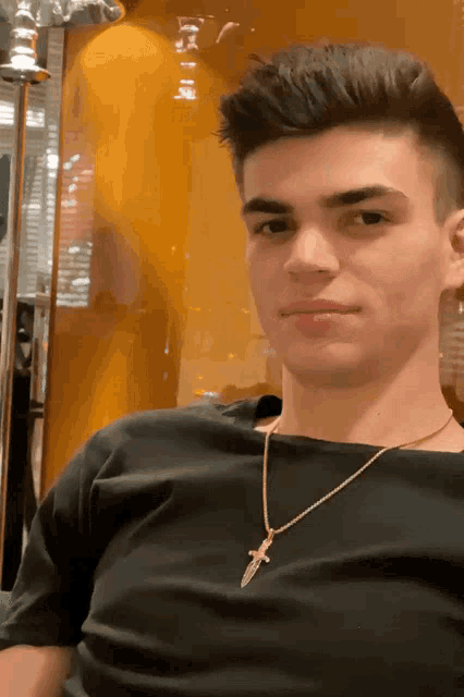 a young man wearing a gold necklace with a cross on it