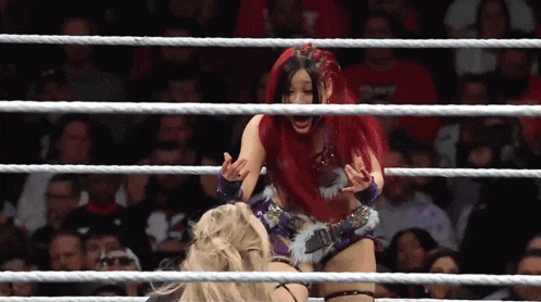 a woman with red hair is in a wrestling ring with a crowd watching