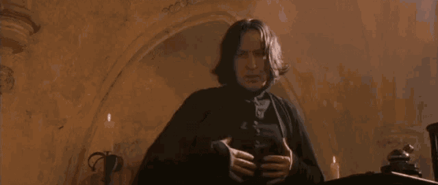 a man is standing in a dark room with a candle in the background .