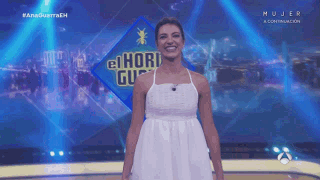 a woman stands on a stage in front of a sign that says el ho