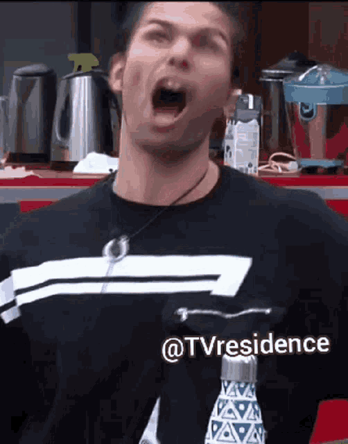 a man wearing a black shirt with a white stripe on it is screaming in a kitchen with the words @tvresidence below him