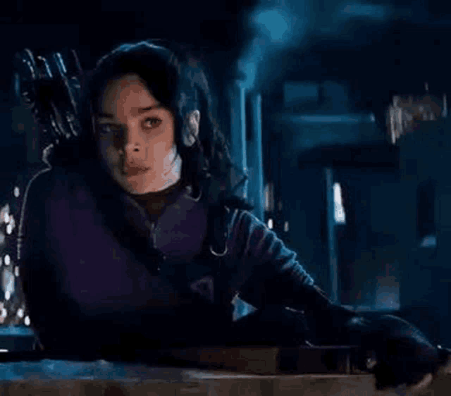 a woman in a purple sweater is holding a bow and arrow .