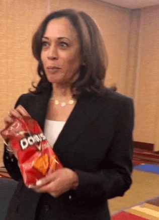 a woman in a suit is holding a bag of doritos .