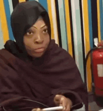 a woman wearing a hijab is sitting at a table with a cell phone .