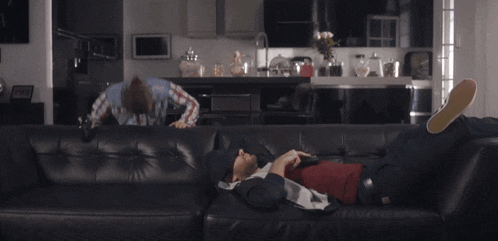 a man laying on a couch with a remote control