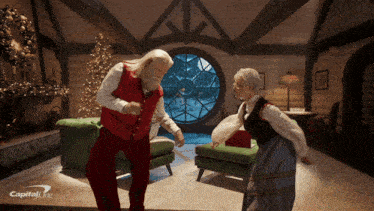 santa claus and a woman are dancing in a room with capital one written on the bottom