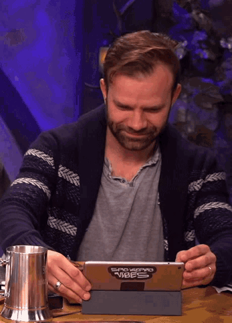 a man sitting at a table looking at a tablet with the word vibes on the front