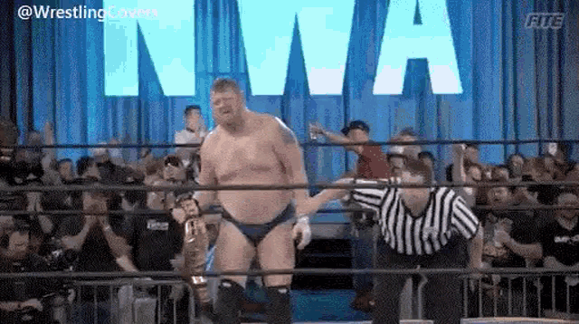 a man in a wrestling ring holding a championship belt .