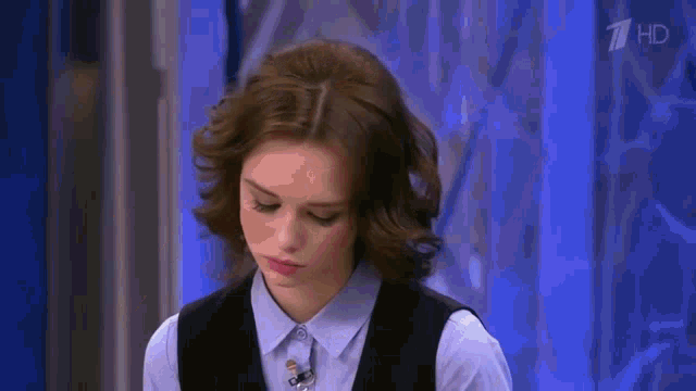 a woman in a blue shirt and black vest on a tv show