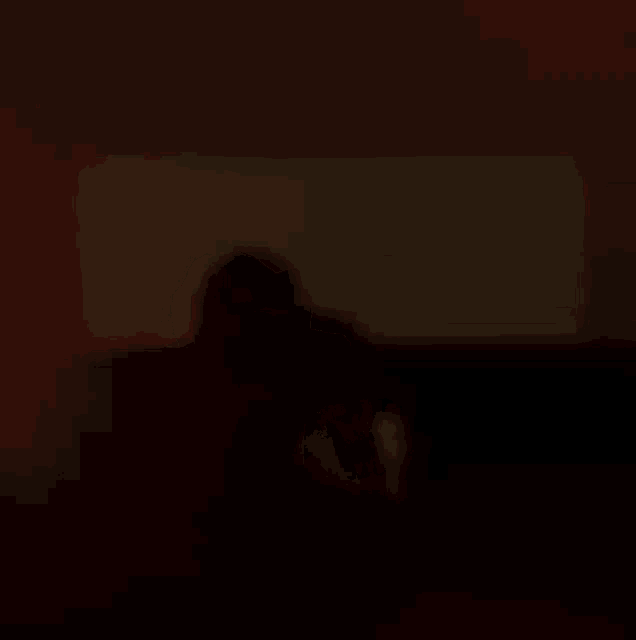 a person is sitting in a dark room watching a movie on a screen