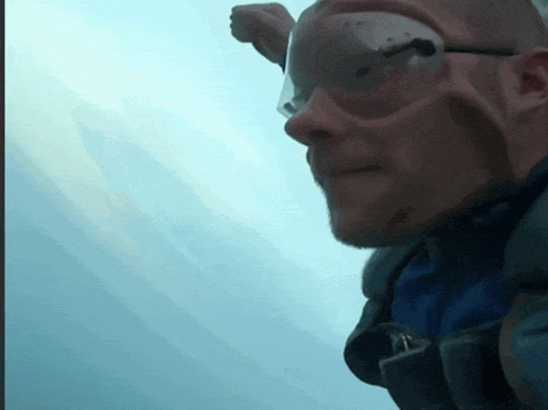 a man wearing glasses and a blue shirt looks at the sky