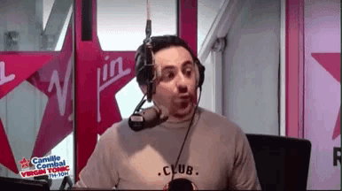 a man wearing headphones and a shirt that says club is talking into a microphone
