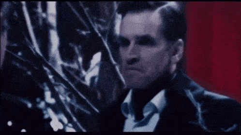 a man in a black jacket stands in a dark forest