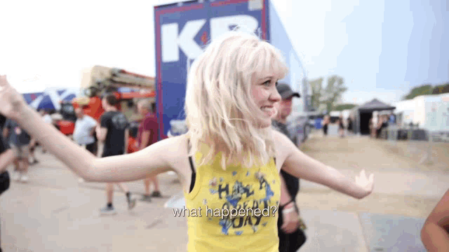 a woman wearing a yellow tank top that says what happened