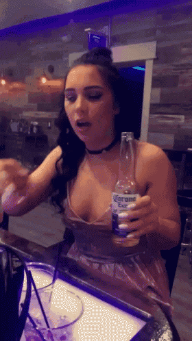 a woman in a plunging neckline holds a bottle of corona