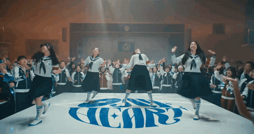 a group of people are dancing in front of a sign that says " heart "