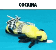 a stuffed bee is laying on a blue surface with a straw sticking out of its mouth .