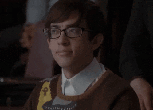 a young man wearing glasses and a sweater with a picture of a monkey on it