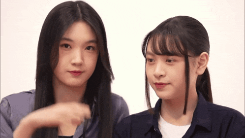 two young girls are looking at each other and one is pointing