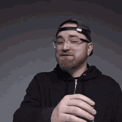 a man with a beard wearing glasses and a hat is making a funny face and says woah !