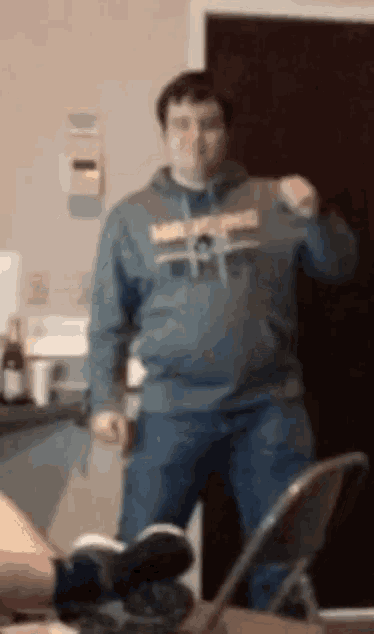 a man wearing a sweatshirt that says washington is standing in a kitchen